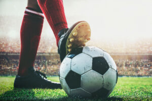 Füße eines Fußballspielers treten auf den Fußball zum Anstoß im Stadion